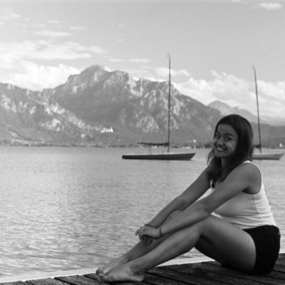 Nicolle am Steg der Forggensee Yachtschule mit dem Dyas-Bojenfeld und den Alpen  im Hintergrund