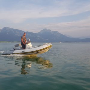 Segellehrer auf dem Elektro-Motorboot vor der wunderschönen Alpenkulisse und Schloss Neuschwanstein