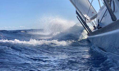 Die Gischt spritzt am Bootsrumpf beim Segeltörn im Mittelmeer Seemeilen sammlen im SKS, SSS oder SHS Törn