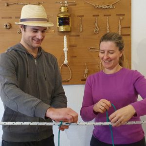 Philipp unterrichtet Knotenkunde an einer Leine im Kursraum. Die Dame ist sichtlich erfreut über ihre Vortschritte.