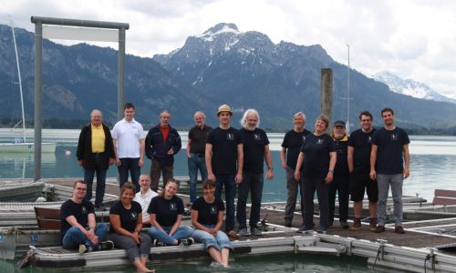 16 Teammitglieder der Forggensee Yachtschule am Steg der Segelschule